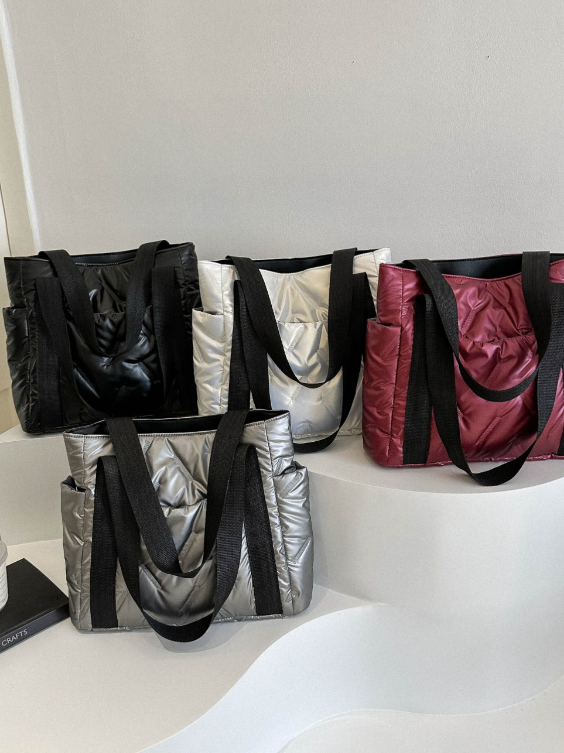 Solid color tote bags in black, silver, white, and burgundy with sturdy straps and a stylish design.