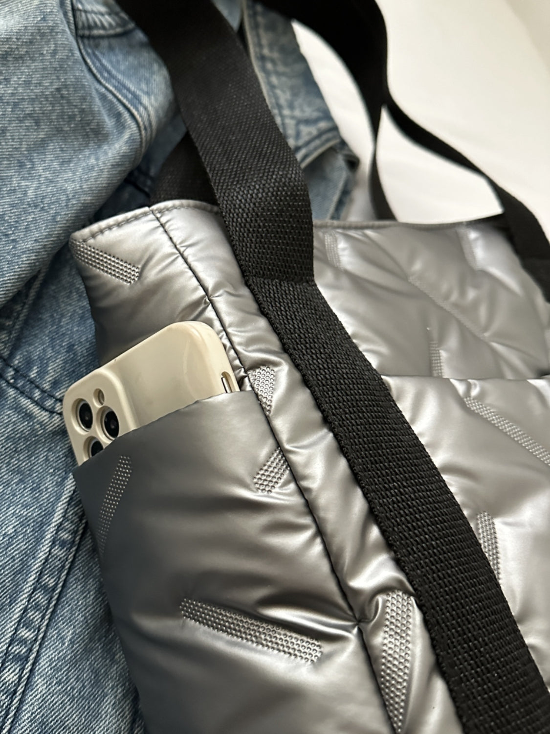 Close-up of a gray tote bag with side pocket holding a smartphone, showcasing modern design and functionality.