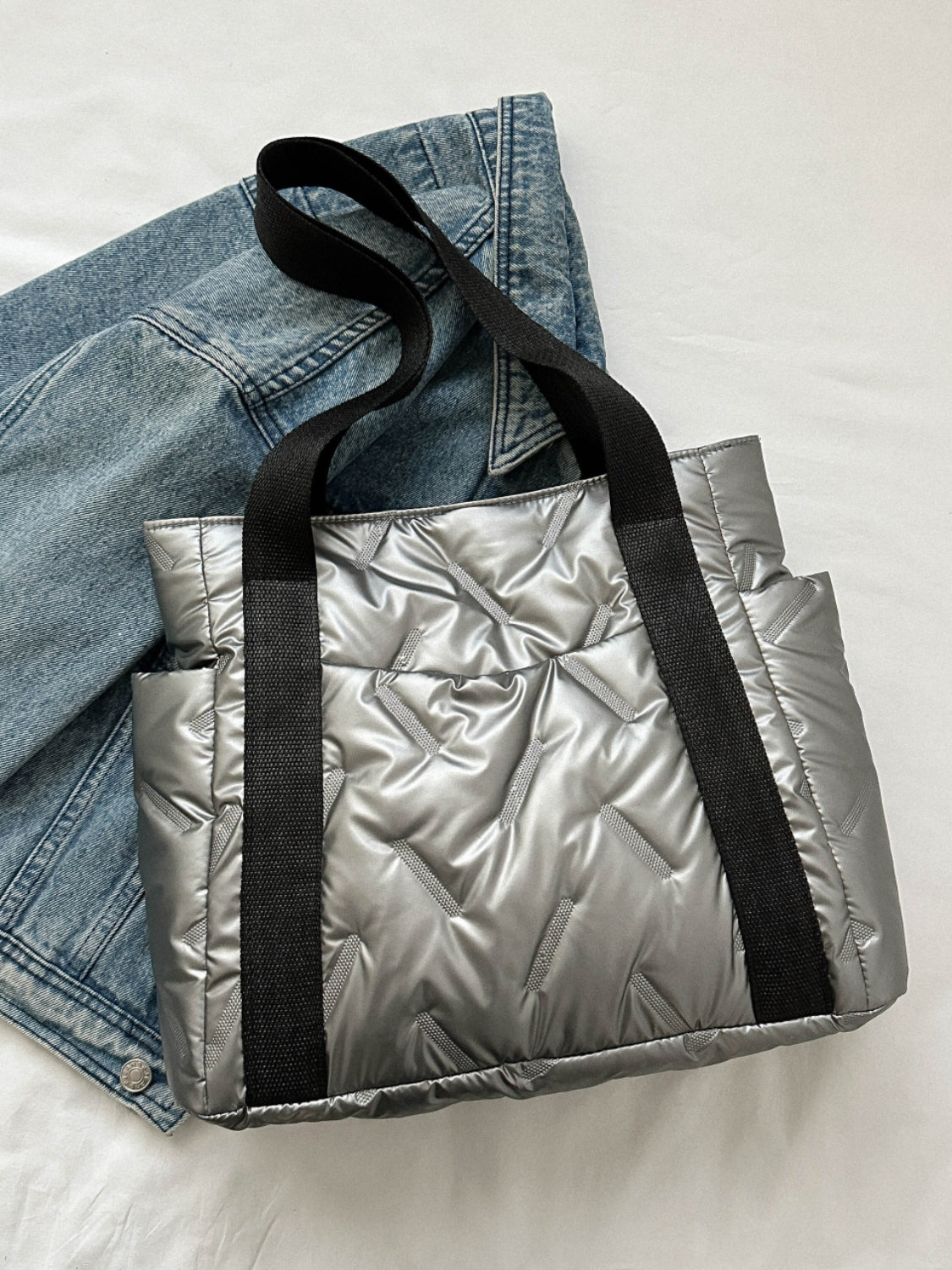 Solid color tote bag made of polyester with side pockets, displayed on a denim jacket background. Large size with a modern design.