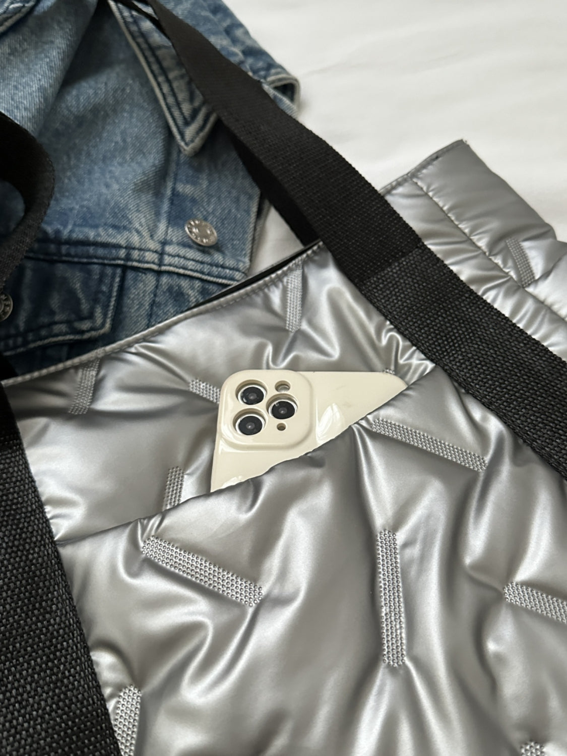 Close-up of a solid color tote bag showing silver interior with a smartphone tucked in, complementing a denim jacket.