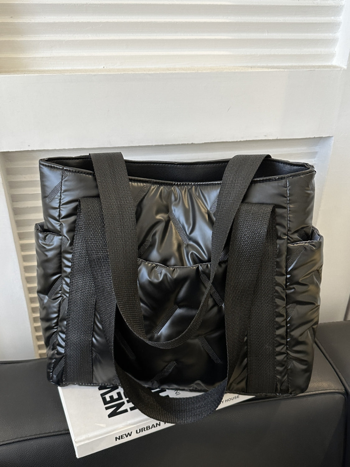 Large solid color tote bag with side pockets in black, made of durable polyester, placed on a magazine.